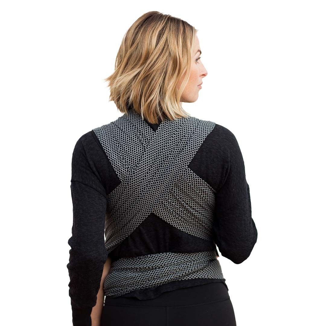 Pano semi-elástico Moby Wrap Flex preto, com o bebé ao colo na posição em M