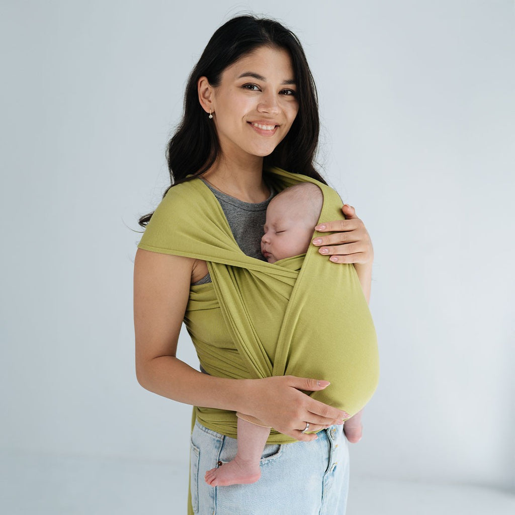 Fular elástico de modal Love and Carry na cor Wasabi, com o bebé ao colo na posição em M