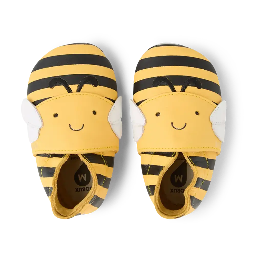 Par de sapatos Bobux Bugbee Abelha, vista superior, com riscas amarelas e pretas, asas e rostos sorridentes.