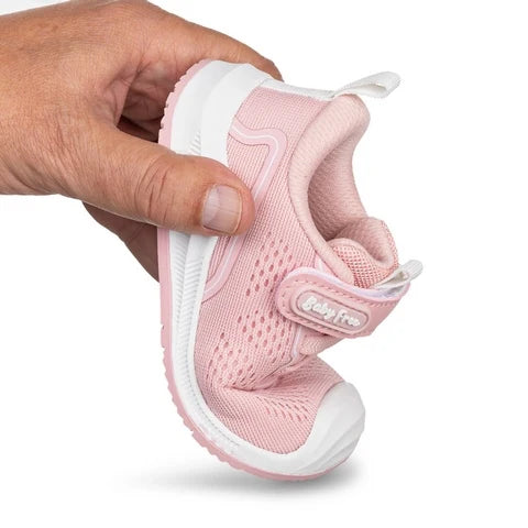 Demonstração da flexibilidade da sapatilha barefoot BabyFree rosa, com a sola a dobrar-se facilmente.