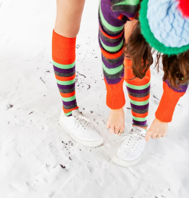 Pessoa a atar os atacadores das sapatilhas Victoria Barefoot OLMO brancas, com meias coloridas, num ambiente que parece neve ou areia clara.