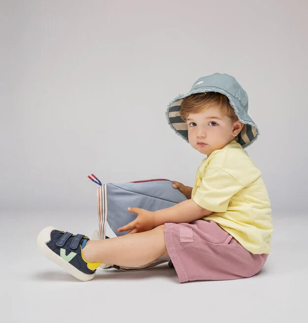 Criança sentada a usar as sapatilhas Victoria Barefoot Oliver, combinadas com roupa de verão.