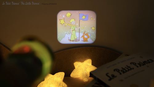 Projeção noturna na parede de uma cena do Principezinho, com estrelas projetadas no ambiente, criando um ambiente de conto de fadas.