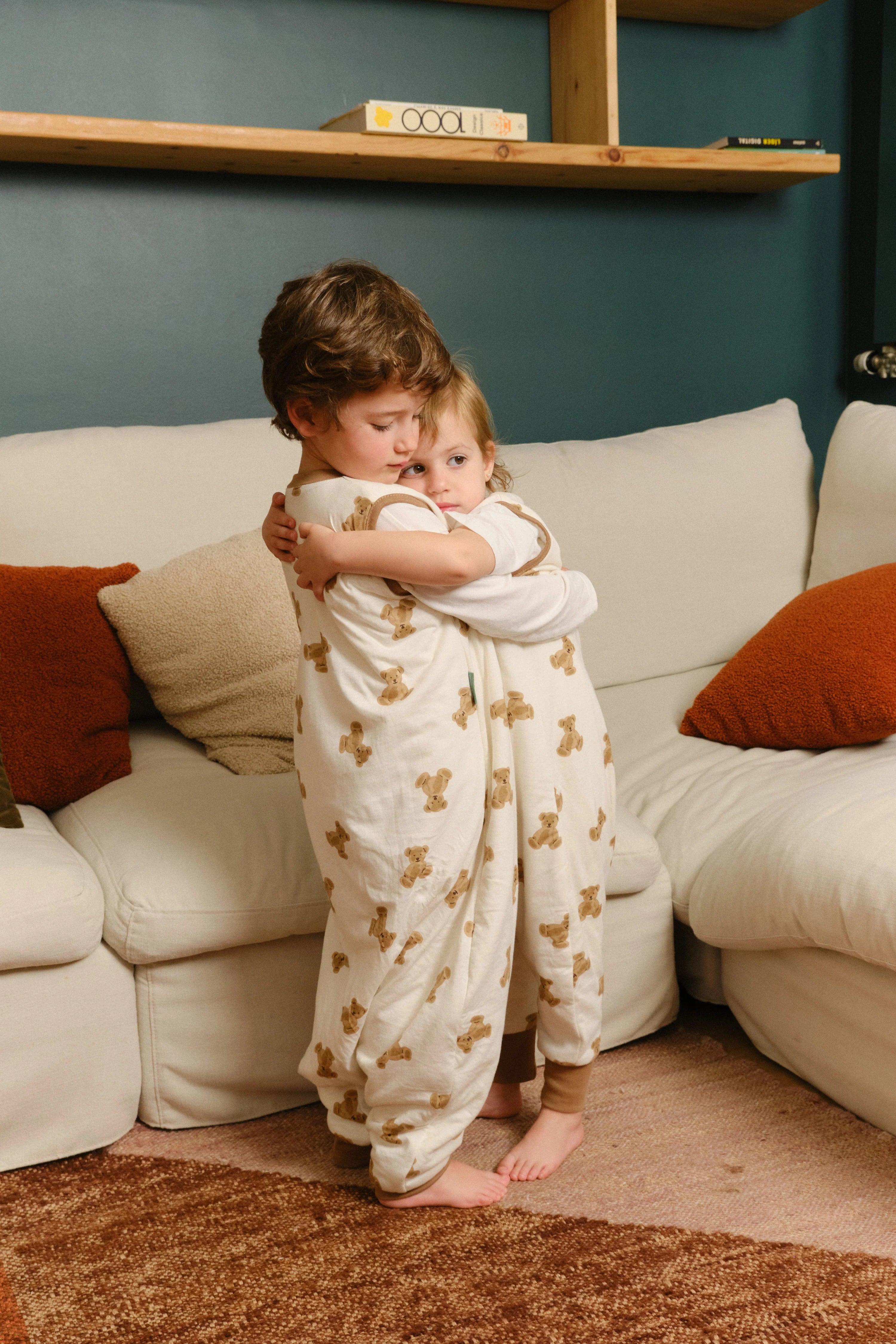 Duas crianças abraçadas, ambas a usar o saco de dormir MolisandCo TOG 1.0 [TEDDY], demonstrando o conforto e a liberdade.