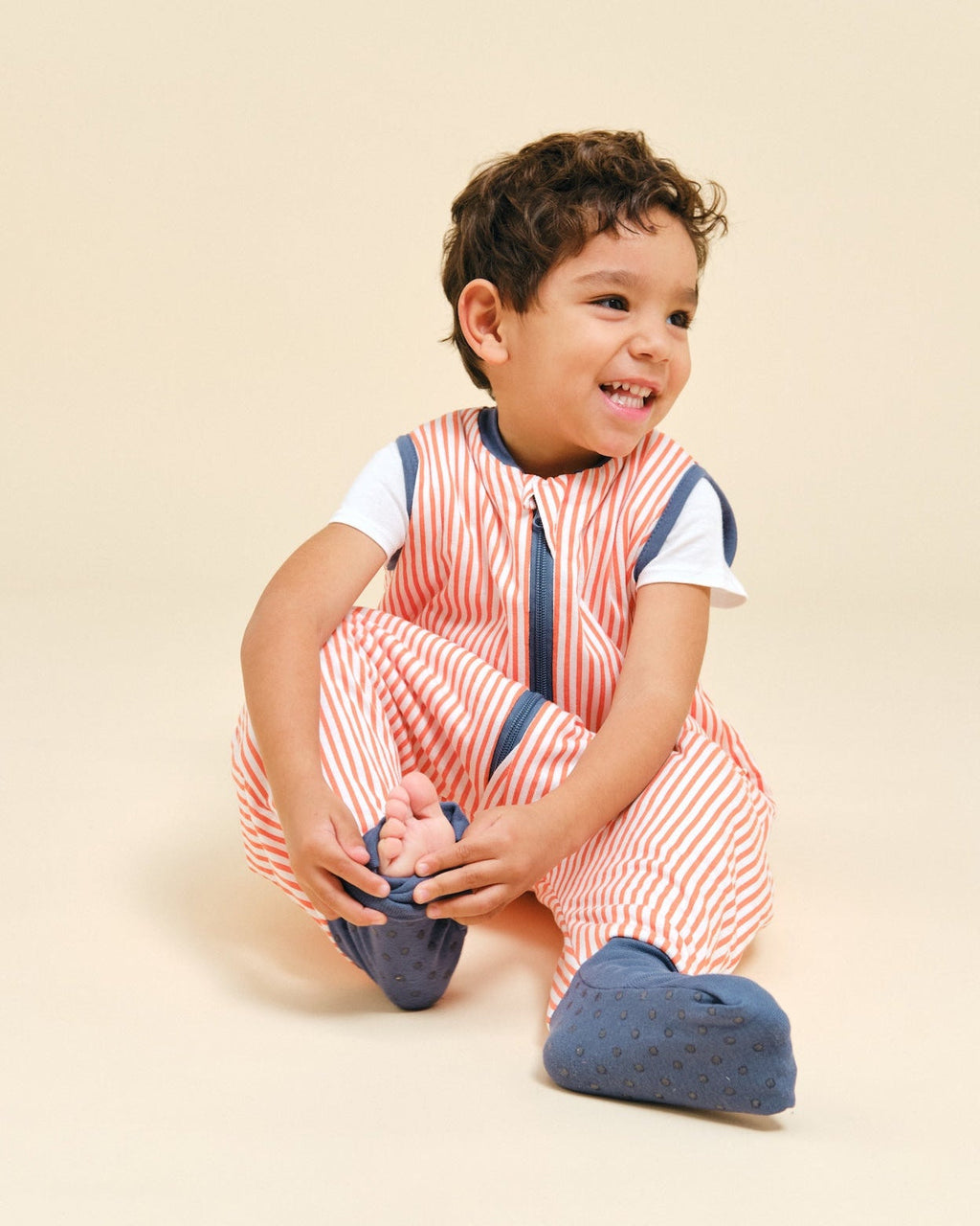 Pijama manta MolisandCo TOG 1.0 com pés e meias antiderrapantes na cor Sailor Orange, vestido por uma criança