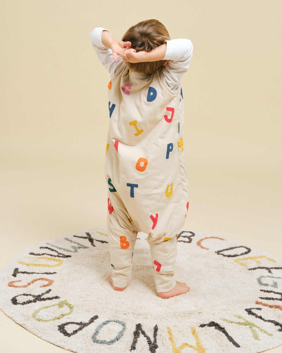Criança vestida com o saco de dormir MolisandCo TOG 1.0 com pés no padrão ABC