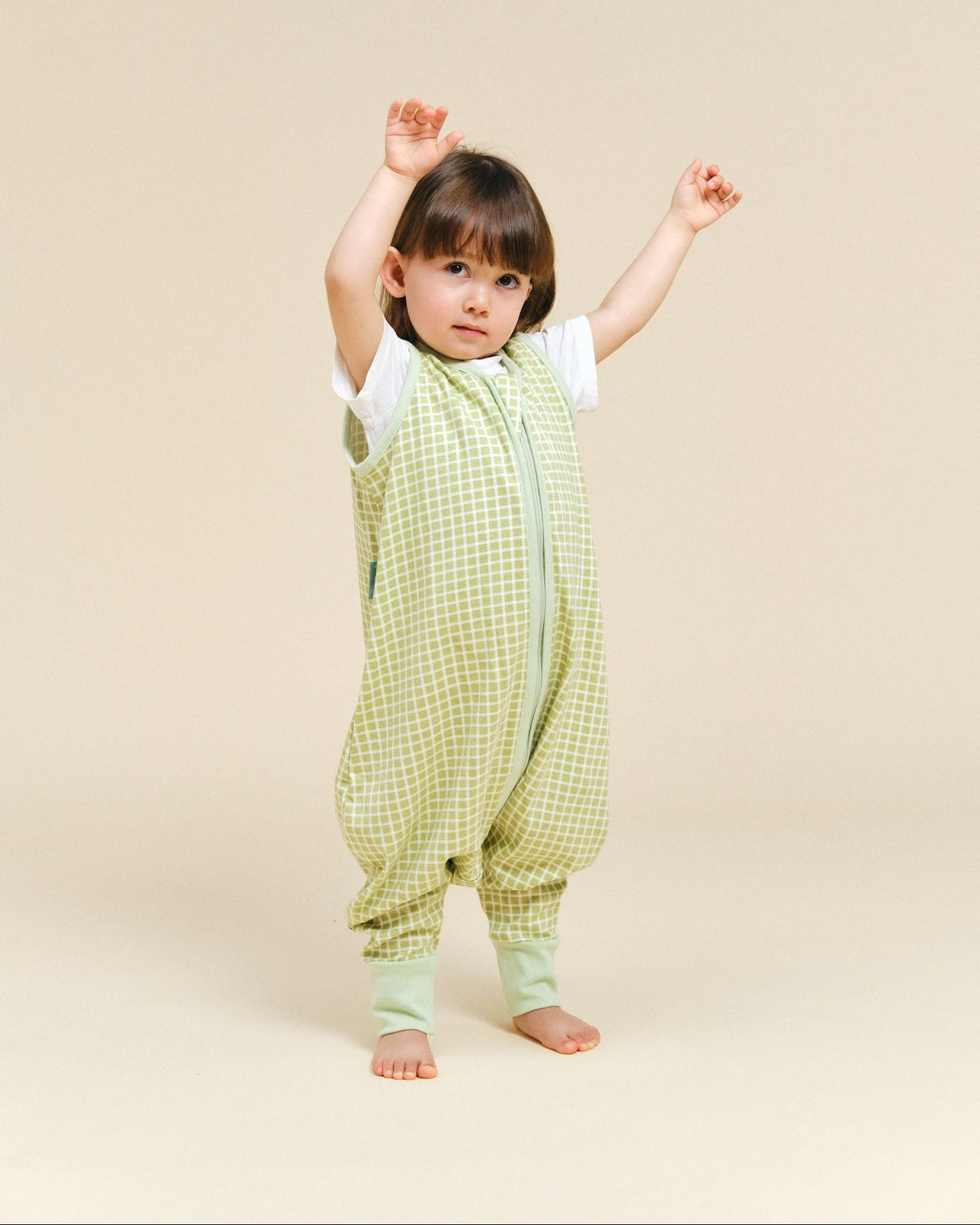 Bebé em pé com o saco de dormir de verão MolisandCo TOG 0.5 em verde pistacchio e pernas separadas