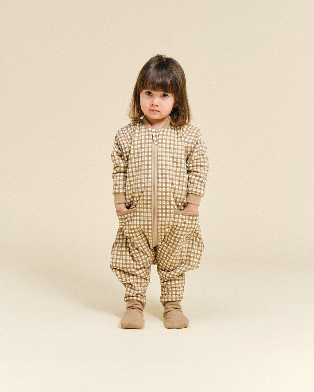 Pijama manta MolisandCo TOG 1.0 com pés e mangas na cor Brown Checks, vestido por uma criança