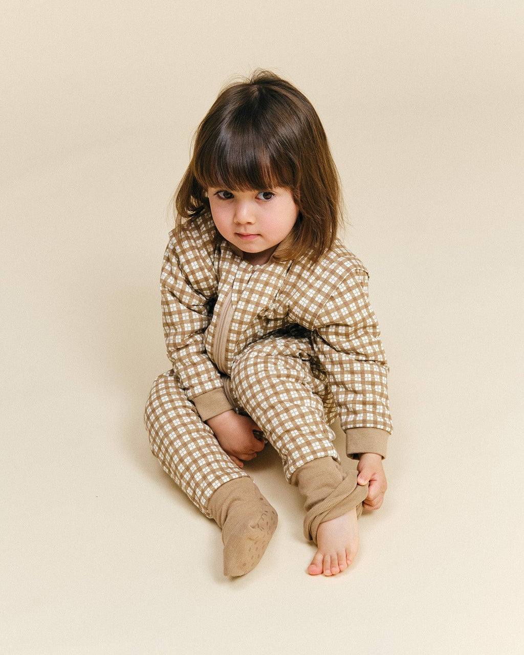 Pijama manta MolisandCo TOG 1.0 com pés e mangas na cor Brown Checks, vestido por uma criança