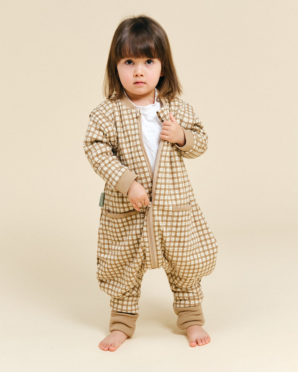 Pijama manta MolisandCo TOG 1.0 com pés e mangas na cor Brown Checks, vestido por uma criança