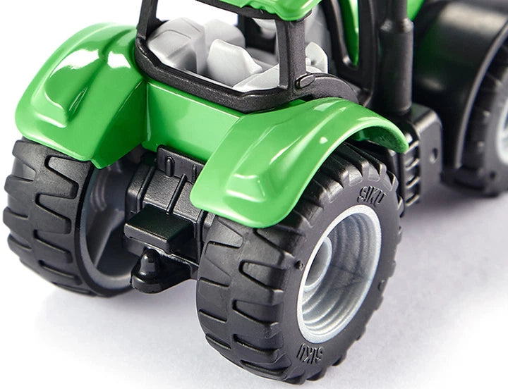 Foco nos detalhes da roda dianteira e na asa do guarda-lamas verde do trator miniatura SIKU, destacando a qualidade do pneu e a construção em metal.