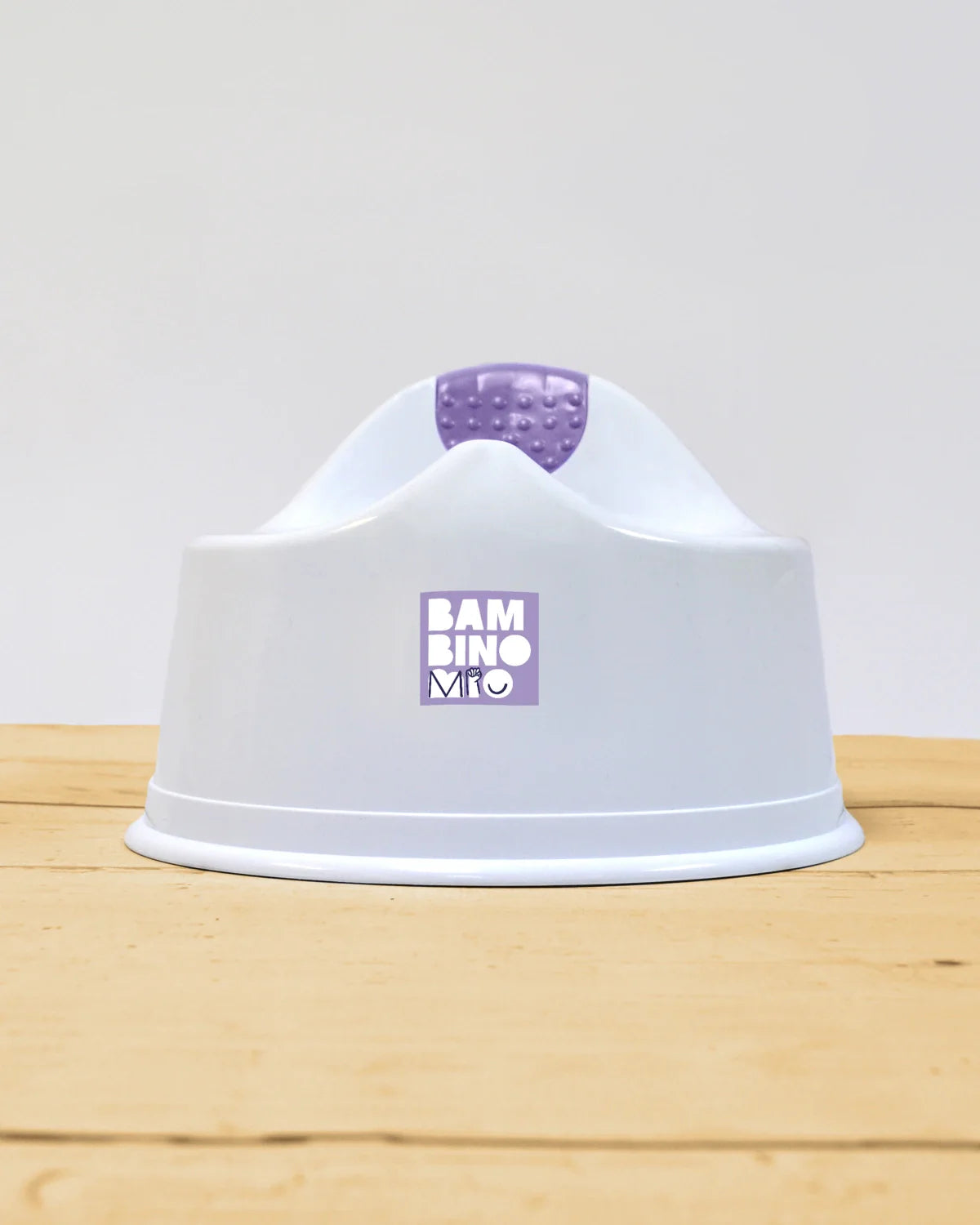Vista frontal do bacio Bambino Mio Pote branco sobre uma superfície de madeira, destacando o logótipo e a forma estável do produto.