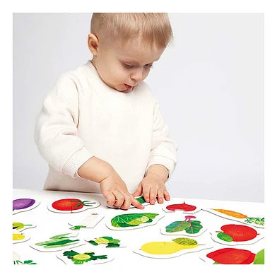Close-up de uma criança pequena a interagir com os puzzles de frutas e vegetais da Banana Panda, focada em encaixar uma das peças.