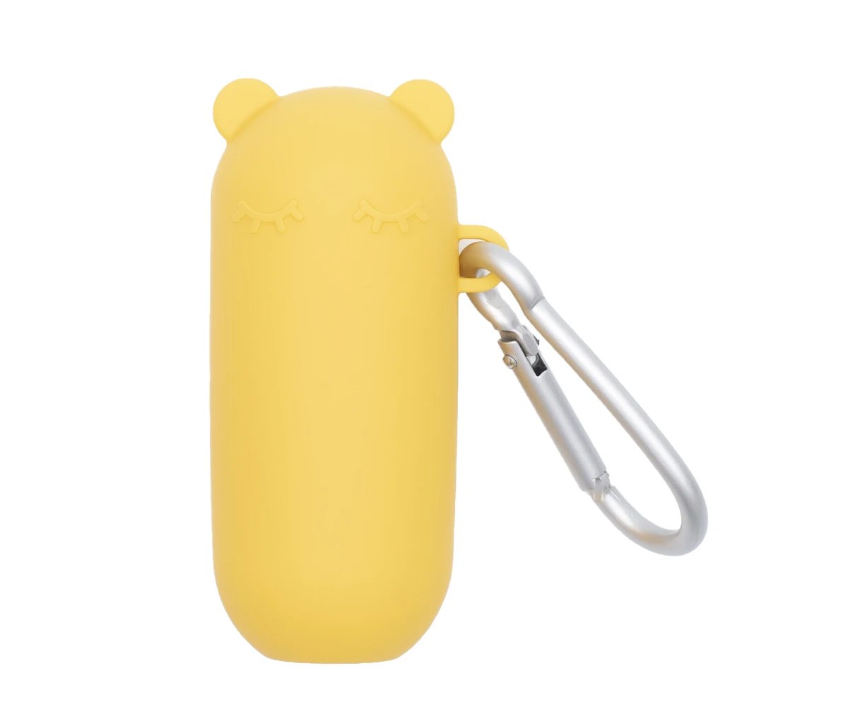 Estojo de silicone amarelo em forma de urso com olhos fechados e mosquetão de alumínio, em fundo branco.