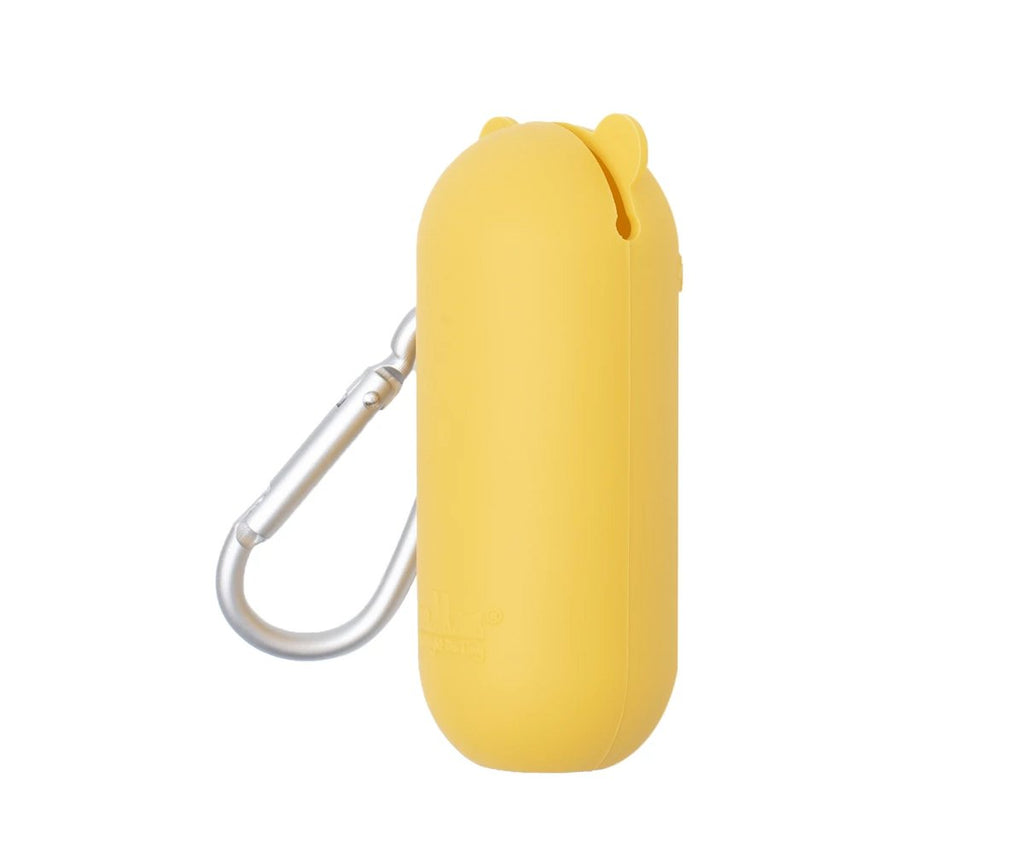 Estojo de silicone amarelo em forma de urso com olhos fechados e mosquetão de alumínio, visto de lado em fundo branco.
