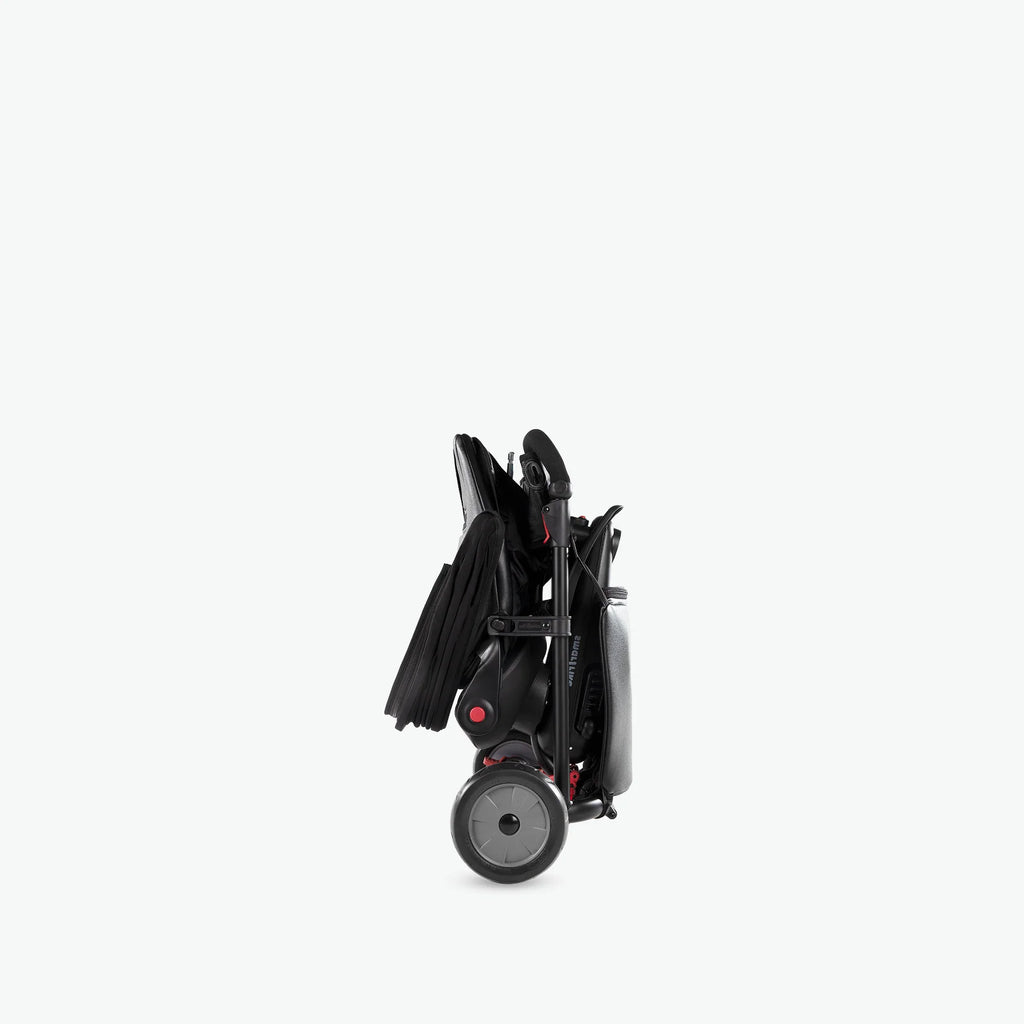 Smartrike STR7 preto dobrado, mostrando o seu formato compacto para fácil transporte e arrumação.