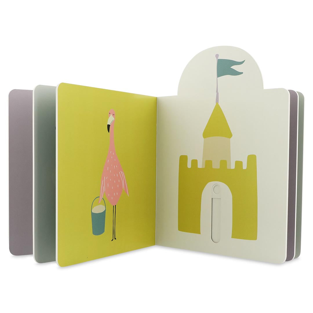 Livro Trixie aberto, mostrando um flamingo cor-de-rosa com um balde e a página seguinte com um castelo de areia com mecanismo de deslizar.
