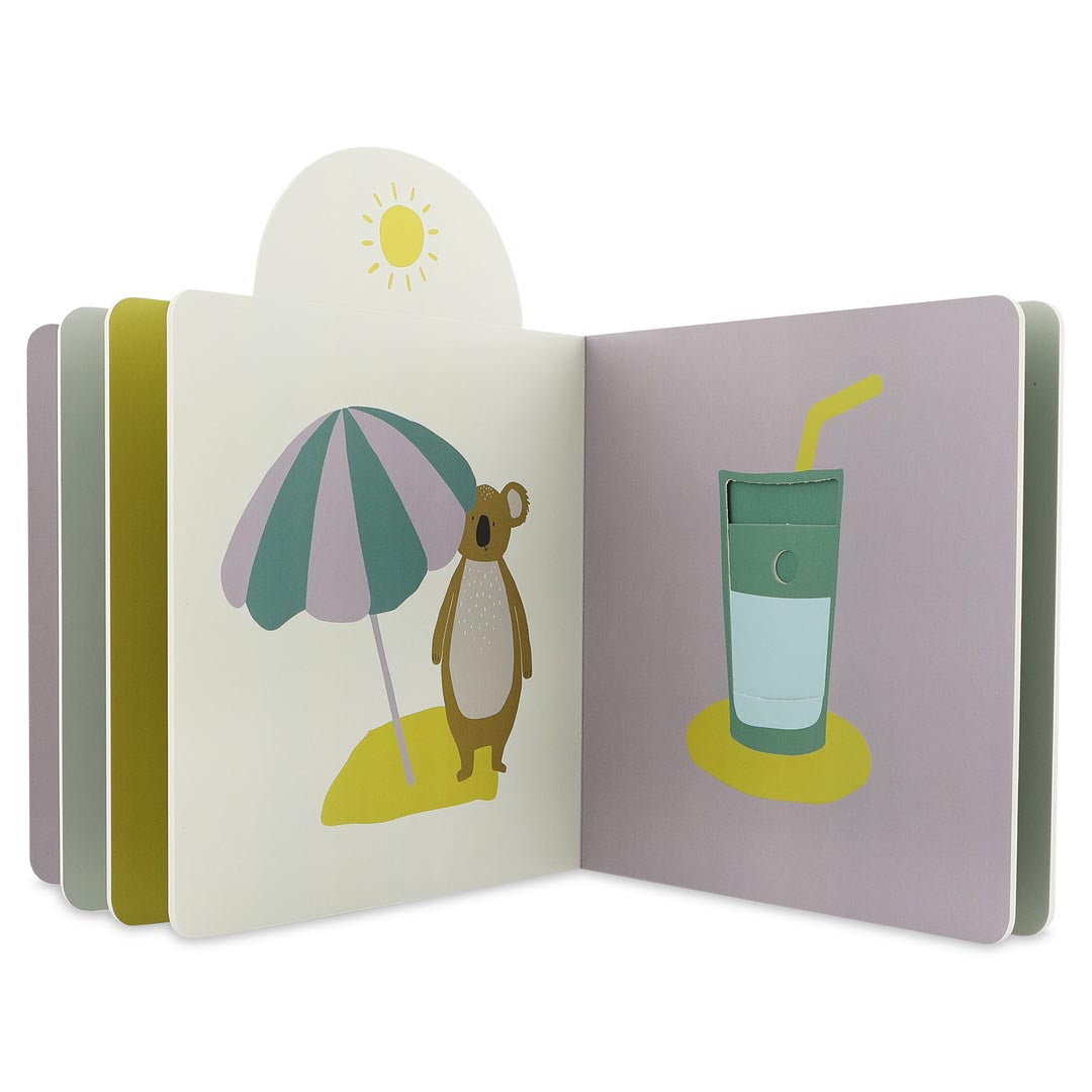 Livro Trixie aberto, mostrando um koala debaixo de um chapéu de sol e a página seguinte com um copo de bebida gelada.