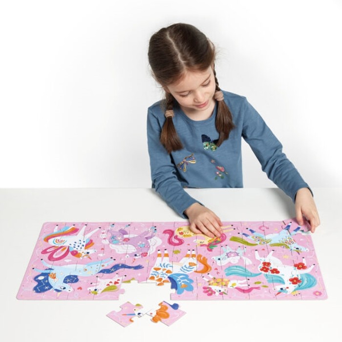 Criança com tranças a montar o Banana Panda Puzzle I Love Unicorns, mostrando o jogo em ação.