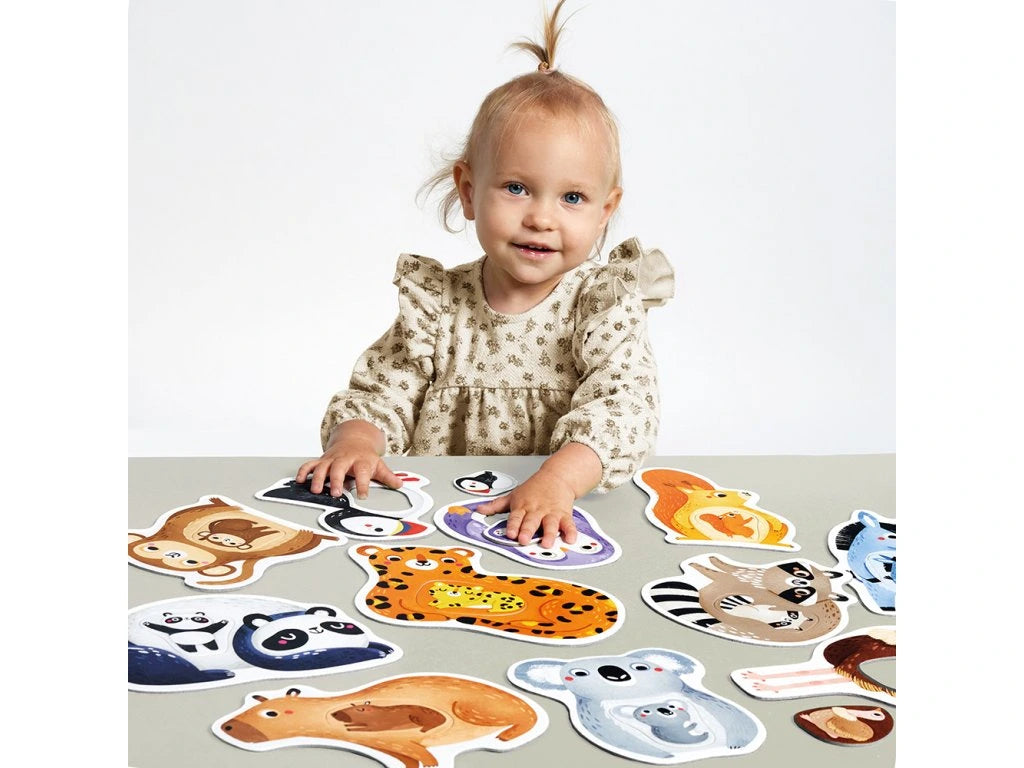 Criança a brincar com o Banana Panda Primeiro Puzzle Jumbo – Mamãs e Bebés, com peças de animais espalhadas na mesa.