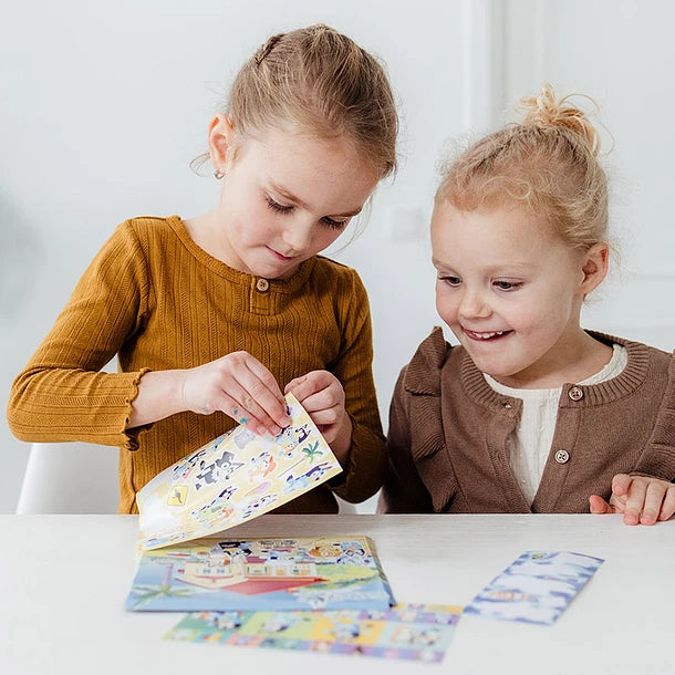 Duas crianças a brincar e a colar os autocolantes Bluey, demonstrando a diversão e o uso do produto.