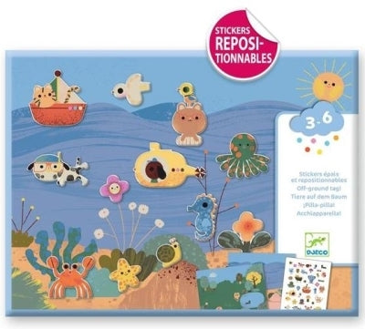 Conjunto Djeco Autocolantes Reposicionáveis - Verão, mostrando a caixa com autocolantes de criaturas marinhas e elementos de verão sobre um cenário de fundo do mar, com o selo "Stickers Repositionnables" e a idade recomendada 3-6 anos.