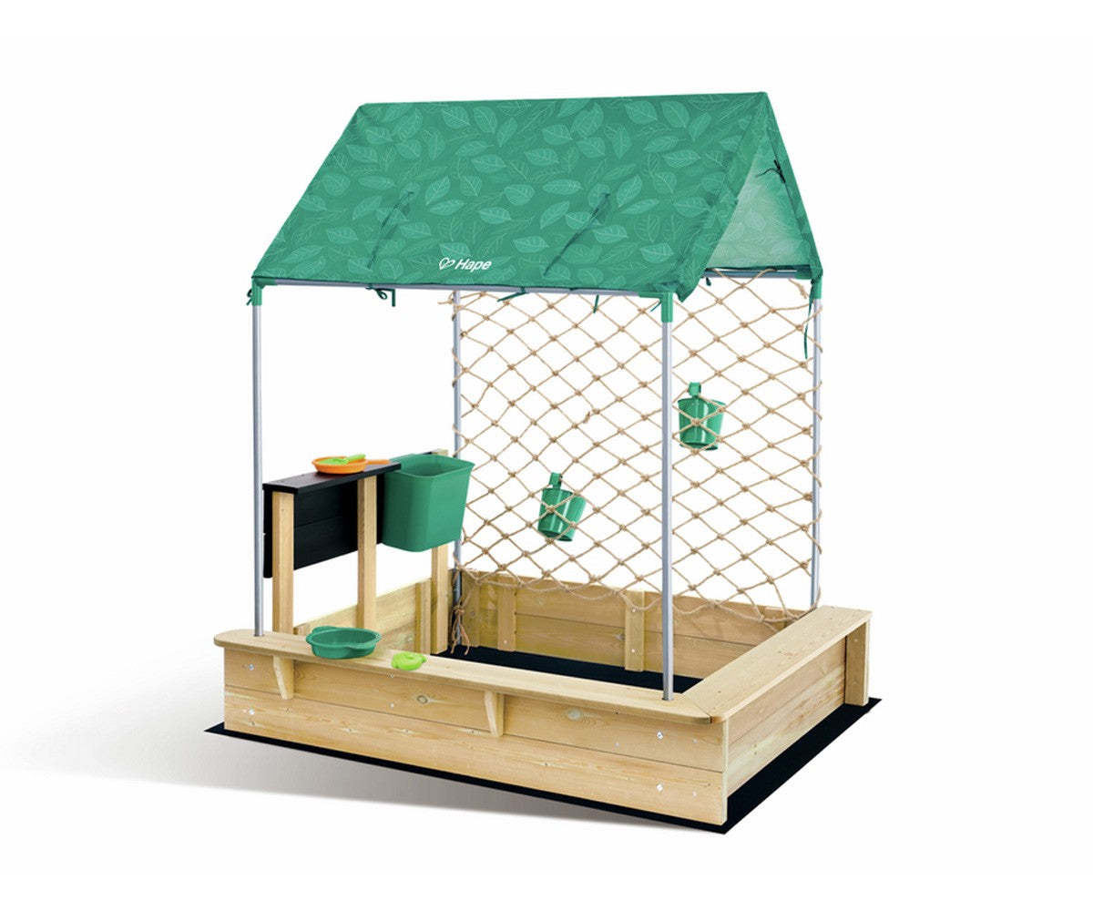 Visão geral do HAPE Set de Cabana e Caixa de Areia, mostrando a estrutura completa com areeiro, cozinha e teto verde com padrão de folhas.