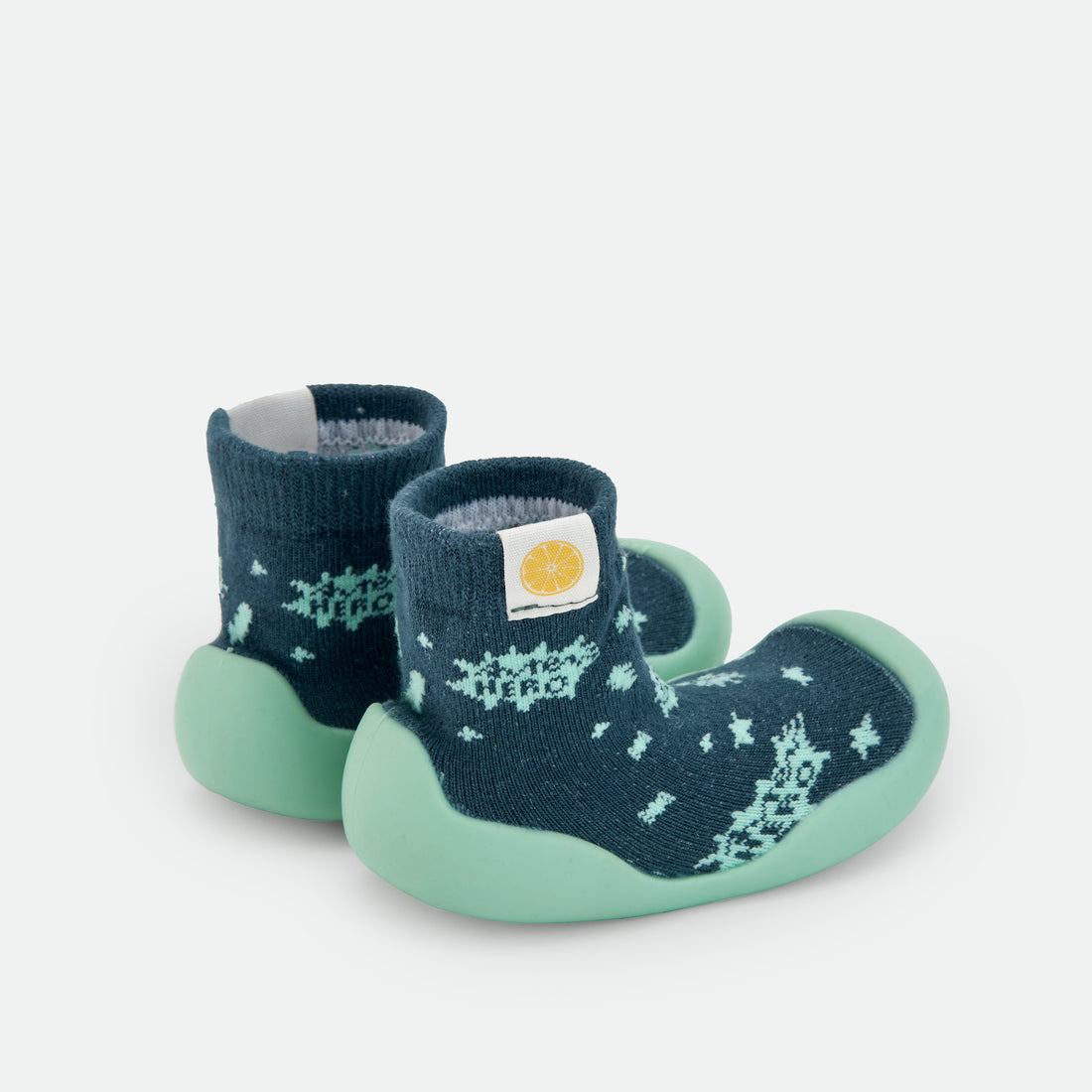 Pantufas tipo meia azul-escuras com sola verde-clara, padrão de constelações, semelhantes às da imagem 1. Uma escolha confortável e segura para crianças em fase de aprendizagem da marcha.
