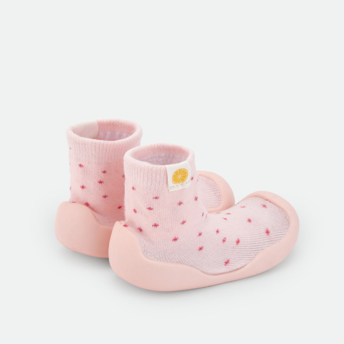 Pantufas tipo meia rosa-claro com sola rosa e pequenos corações vermelhos, iguais às da imagem 3. Uma opção doce e confortável para o dia a dia do bebé.
