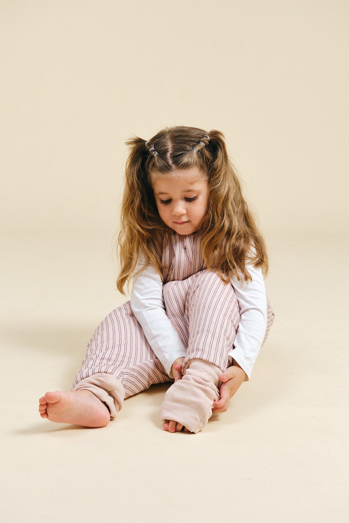 Pijama manta MolisandCo TOG 2.5 com pés e meias antiderrapantes na cor Navy and Pink Stripes, vestido por uma criança