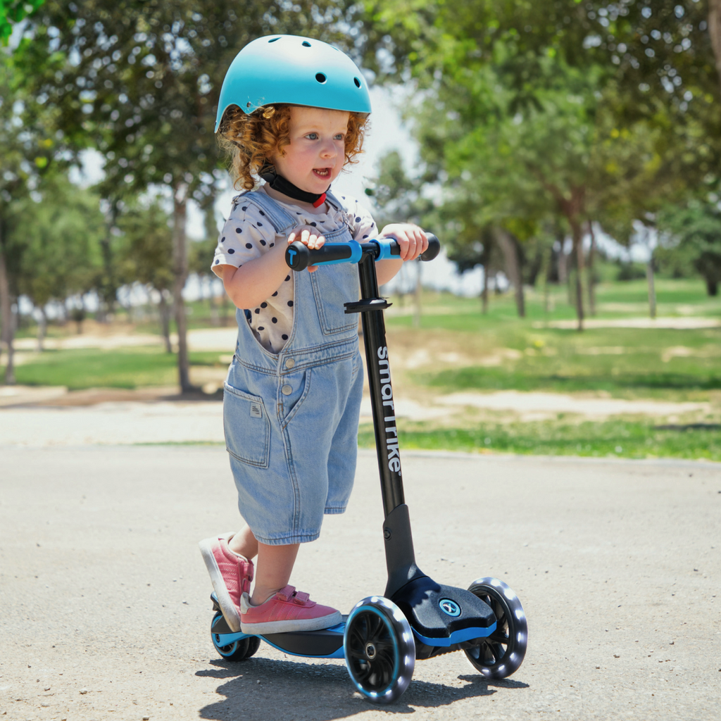 Criança a andar na trotinete Smartrike XTEND Scooter Azul ao ar livre