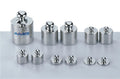 Conjunto de pesos de metal Miniland para balanças educativas, com diferentes tamanhos e pesos, ideal para aprender medição e equilíbrio.
