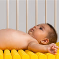 Bebé deitado confortavelmente no colchão Micuna premium HR Perfilado amarelo, mostrando o design ergonómico e a textura perfilada.