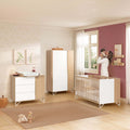 Micuna Amaia Muda-fraldas CP-2025 em Madeira / Branco sobre a cómoda, num quarto de bebé com berço e armário.