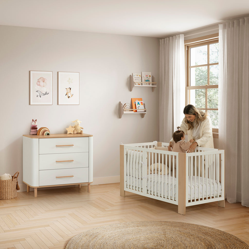 Cómoda Micuna Curve CO-2026 em branco e madeira num quarto de bebé com berço, fotografia oficial da Micuna.