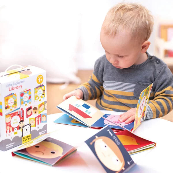 Bebé a brincar e a ler um dos livros em acordeão Banana Panda "Os Meus Sentimentos" numa mesa, com a caixa do pack ao lado.