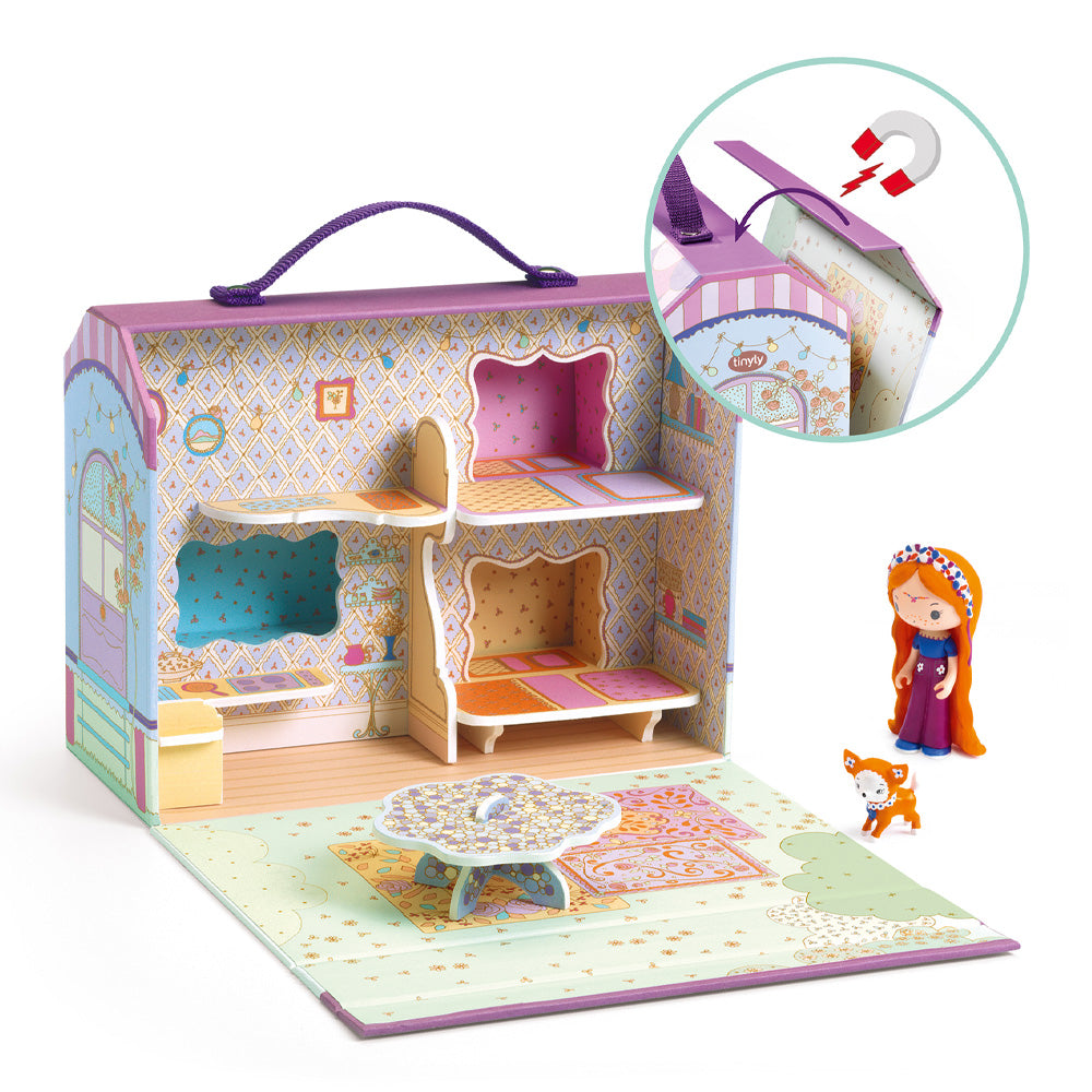 Djeco Tinyly Bluchka & Indie House Casa Caravana aberta, mostrando o interior com decoração vintage, a figurinha Bluchka, o cão Indie, uma mesa e tapetes. Detalhe da pega e fecho magnético.
