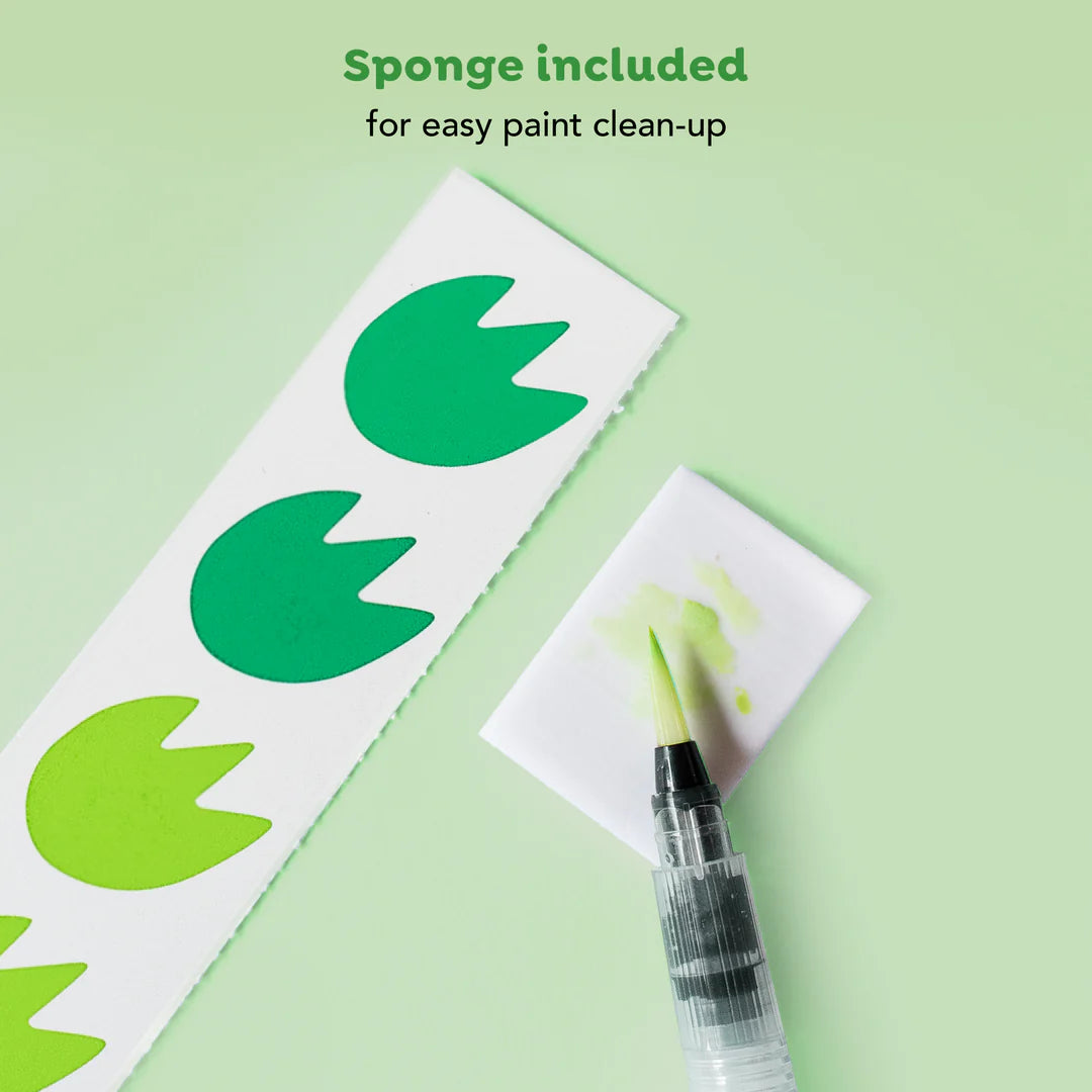 Pincel de água ao lado de uma tira de pigmentos verdes e uma esponja com vestígios de tinta verde, ilustrando a limpeza fácil.