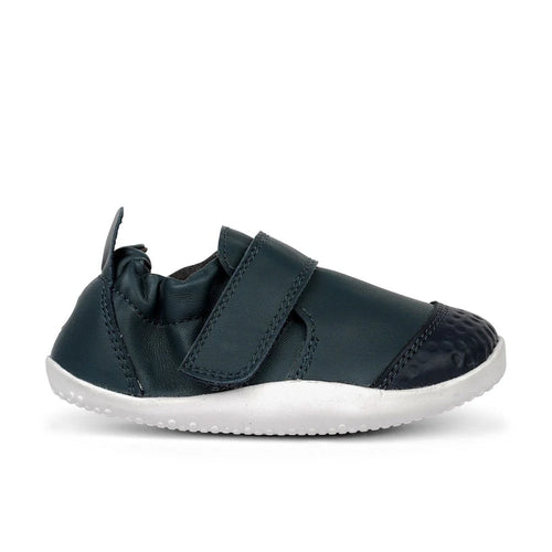 Calçado respeitador Bobux Xplore Navy para bebé, vista lateral, com sola branca flexível e fecho de velcro.