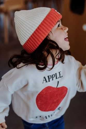 Criança de perfil a usar o gorro HELLO HOSSY Grandma Pink, mostrando o ajuste e o design moderno do gorro.