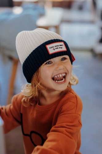 Criança feliz a usar o gorro Hello Hossy Grandma Navy, evidenciando o conforto e a suavidade do tecido orgânico.