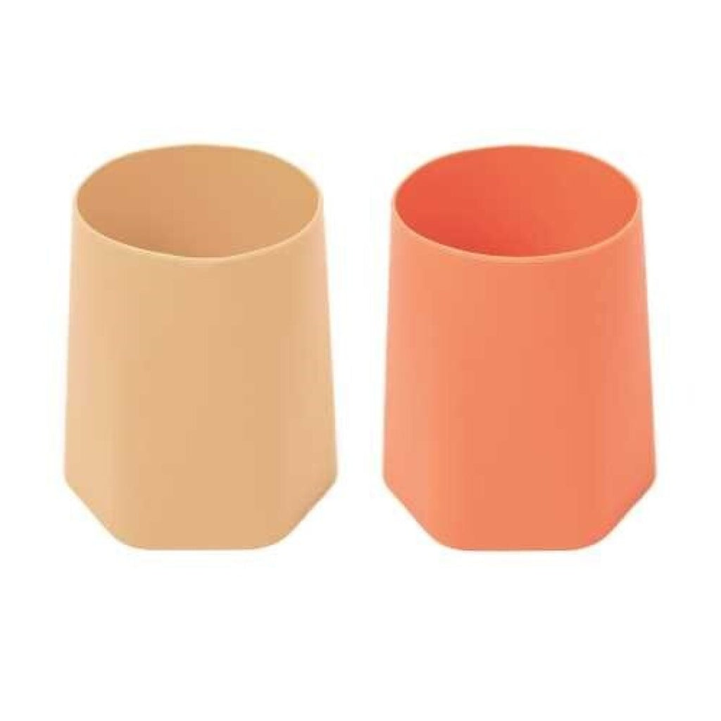 Dois copos de treino abertos de silicone lado a lado: um em tom bege/areia e outro em tom laranja queimado.