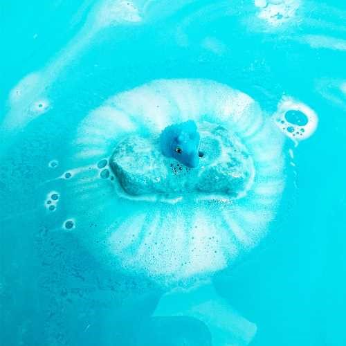 Figura de dinossauro azul a emergir de uma bomba de banho azul efervescente na água da banheira.