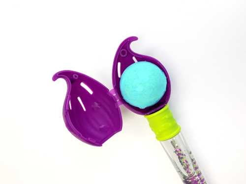 Detalhe do pincel mágico roxo aberto, com uma bomba de banho azul turquesa colocada no seu interior, pronto a usar.