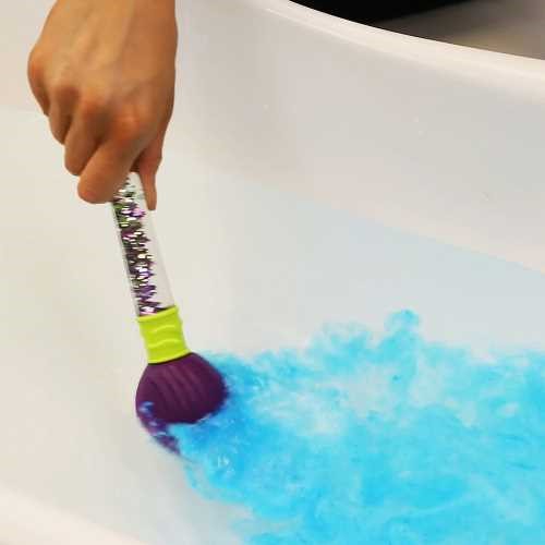 Mão de uma criança a usar o Pincel Mágico Zimpli Kids numa banheira, libertando uma cor azul efervescente na água.