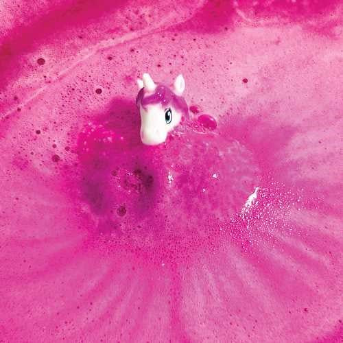 Figura de unicórnio branco e rosa a emergir de uma bomba de banho rosa efervescente na água da banheira.