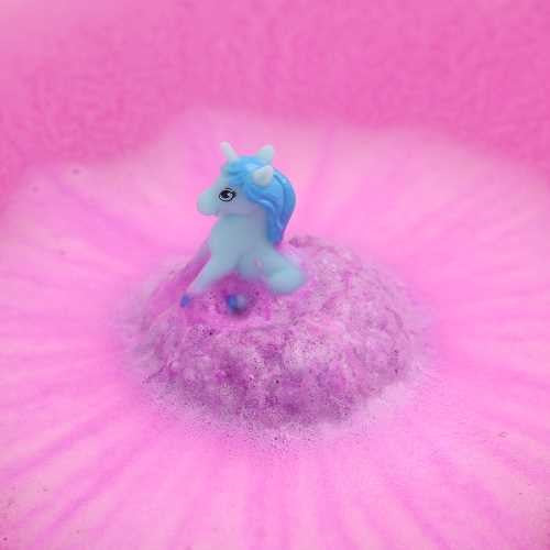 Figura de unicórnio azul claro e roxo a emergir de uma bomba de banho rosa efervescente na água.
