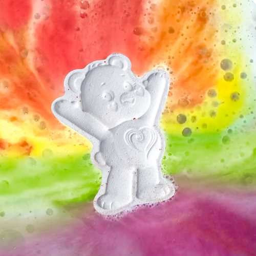 Close-up da ZIMPLIKIDS Bomba de banho Urso Amoroso branca a efervescer em água colorida com tons de arco-íris.