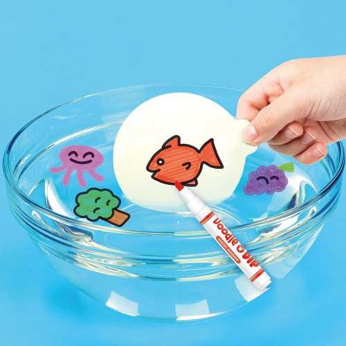 Criança a desenhar um peixe vermelho numa paleta branca a flutuar numa tigela de água, com outros desenhos coloridos a flutuar ao redor.