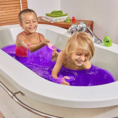 Duas crianças sorridentes a brincar e interagir com o slime púrpura dentro de uma banheira.